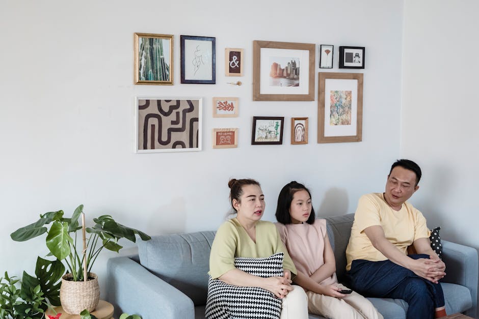 A family of three sits together on a sofa in a stylish living room, enjoying lei