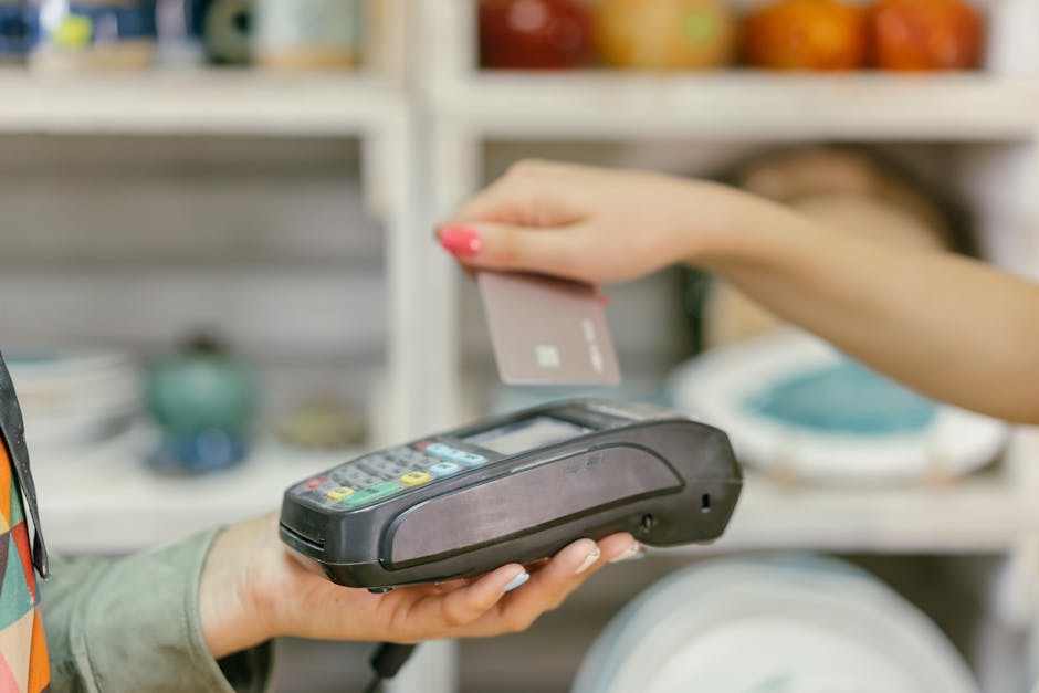A hand using a credit card for payment at a point of sale terminal, close-up vie