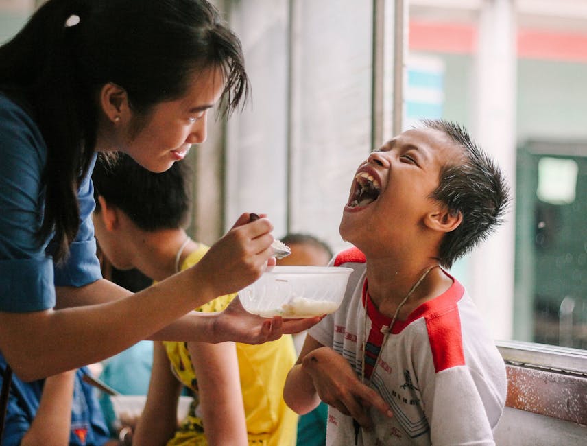 Joyful moment as a woman feeds a happy child in a warm, indoor setting.