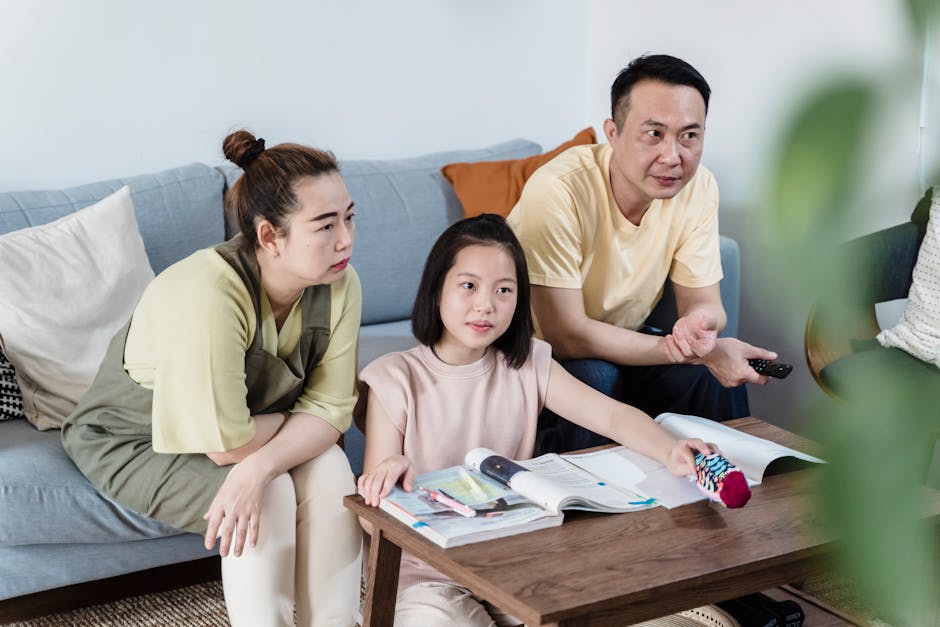 A family of three spending quality time indoors, seated on a couch with books an