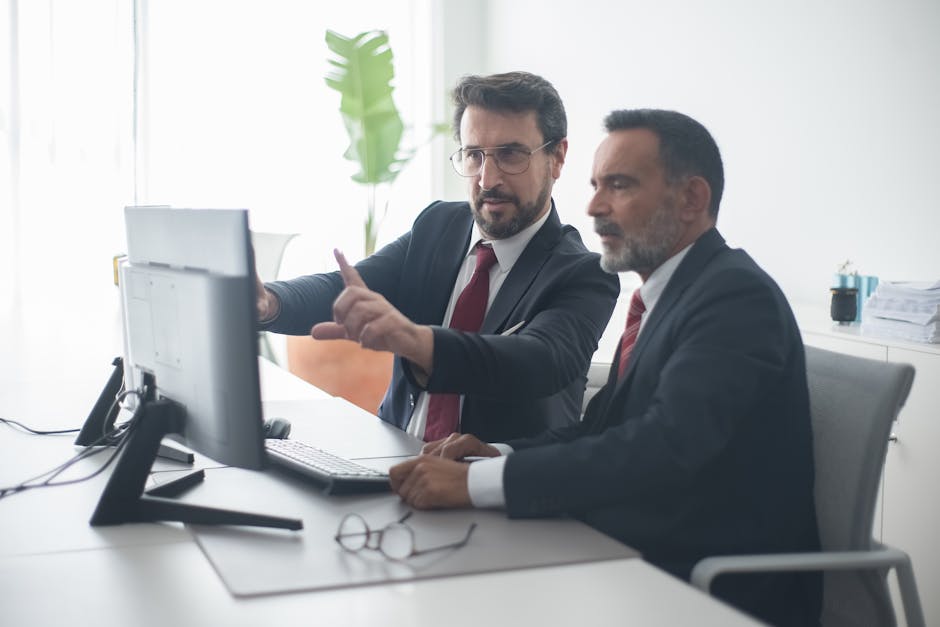 Two male colleagues collaborating on a project at the computer in a bright, mode