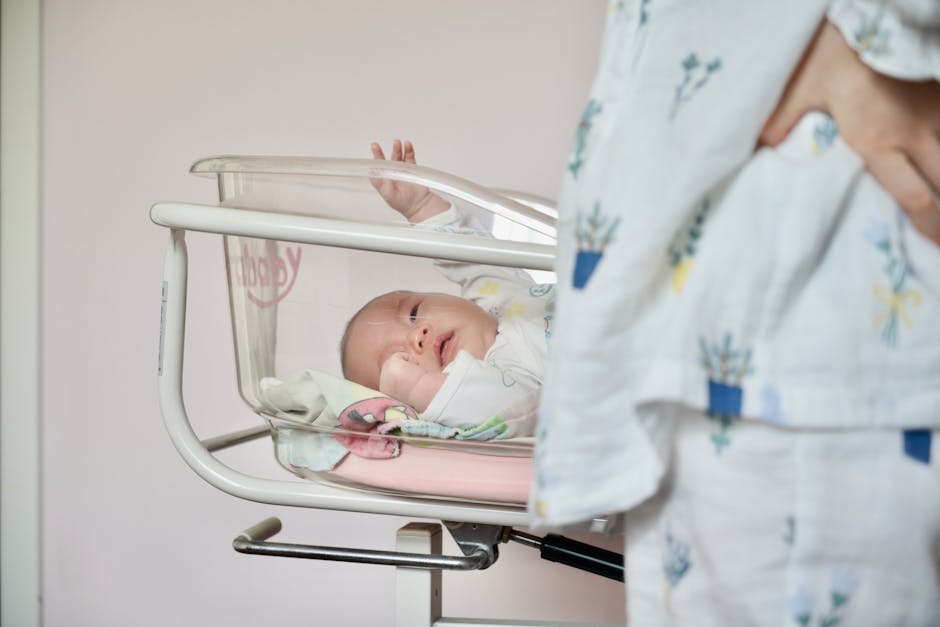 A tender scene of a newborn baby lying in a hospital bassinet with the mother st