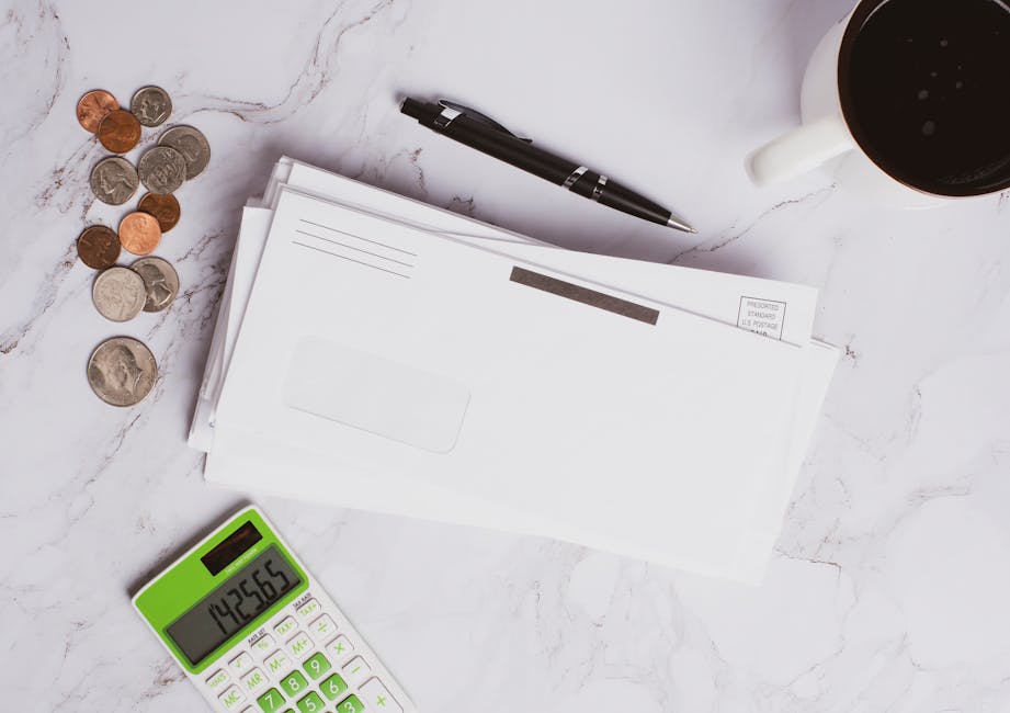 Flat lay of financial documents, calculator, coins, and coffee cup on marble sur