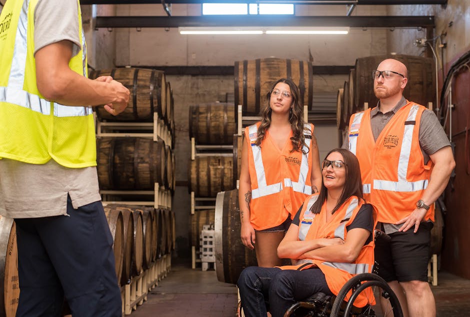 Group of adults in safety vests touring a brewery, highlighting inclusivity and