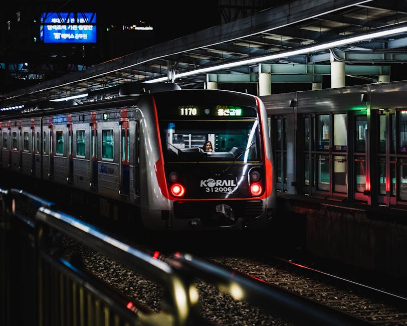 A Korail train at night in a bustling Seoul station, illuminated with vibrant li