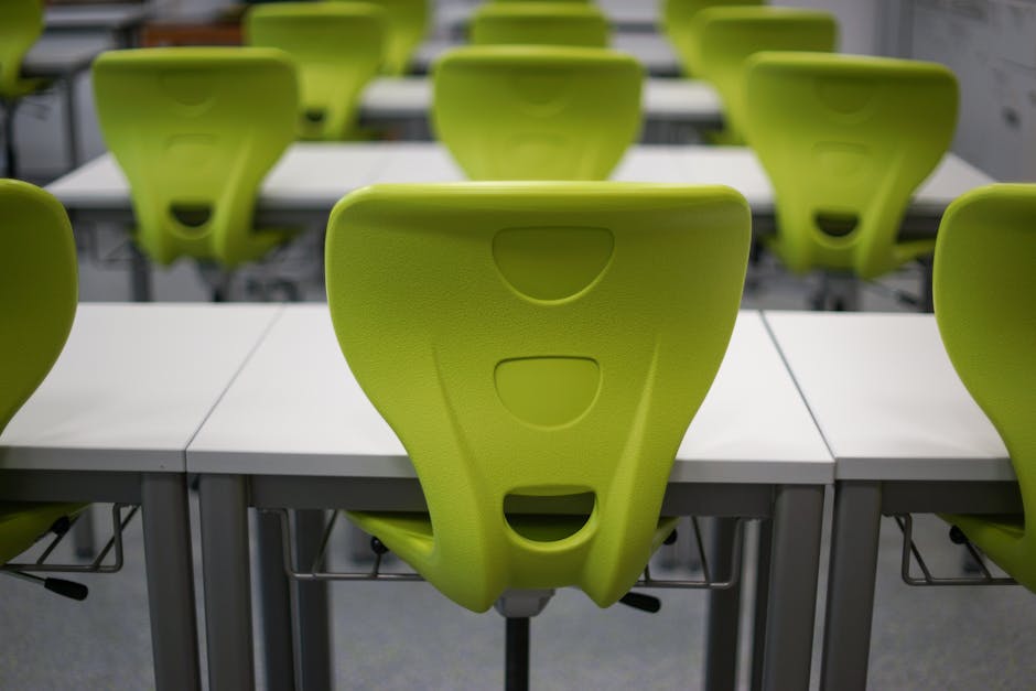 An empty modern classroom featuring rows of vibrant green plastic chairs and whi