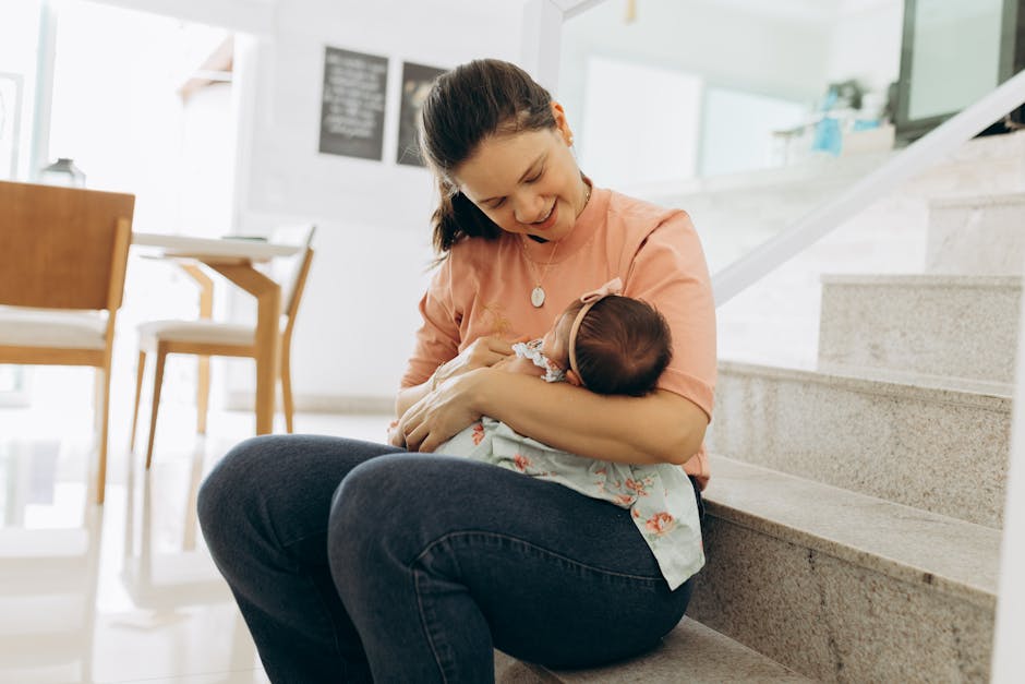 Woman smiling and cradling baby on stairs indoors, portraying warmth and family 