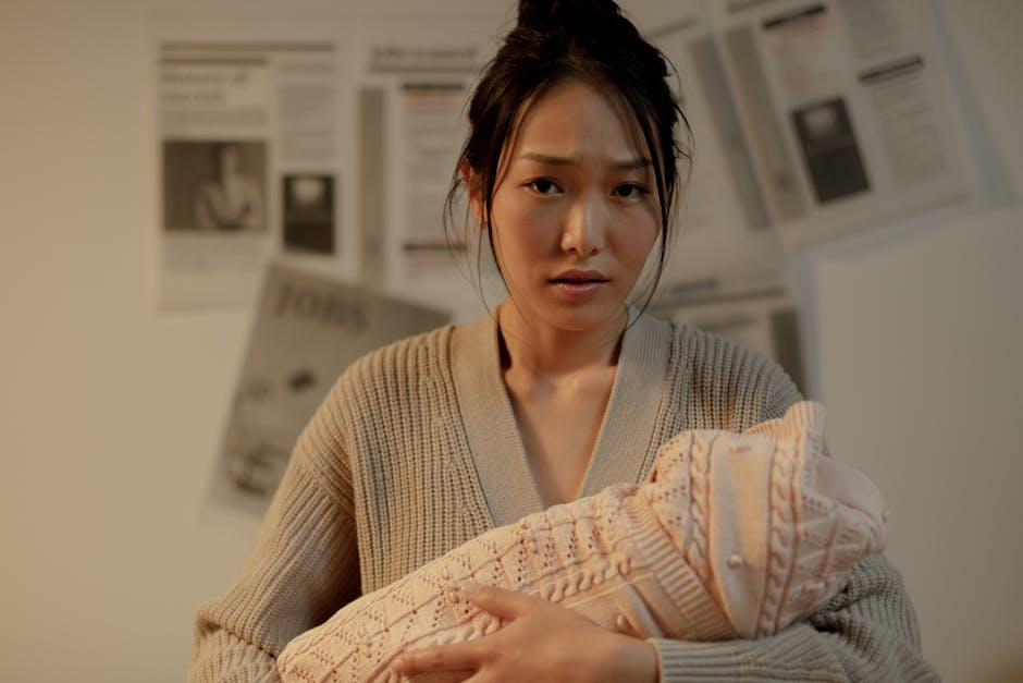 A concerned mother embraces her newborn indoors, surrounded by newspaper article