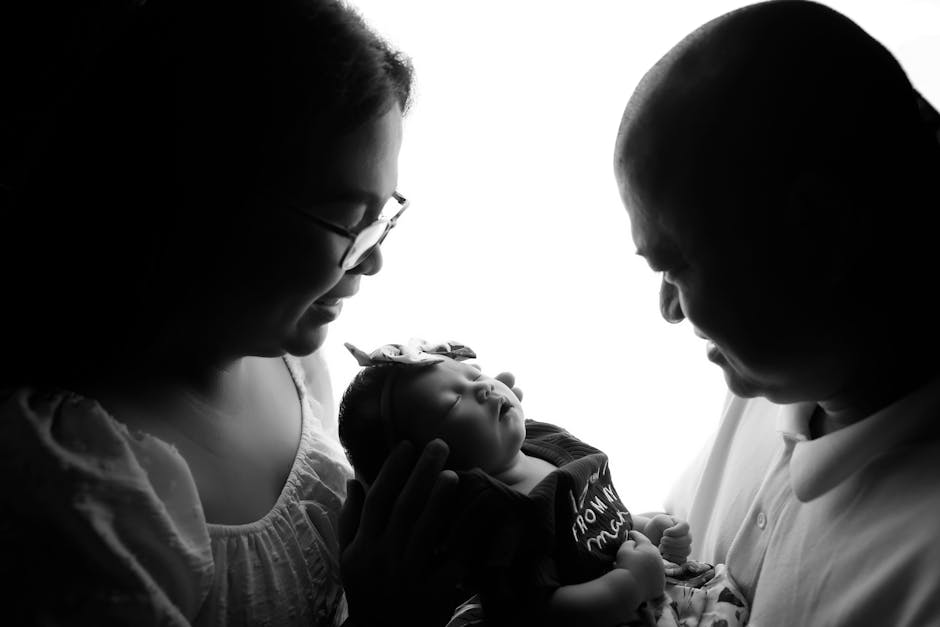 A touching black and white portrait of parents admiring their newborn baby.