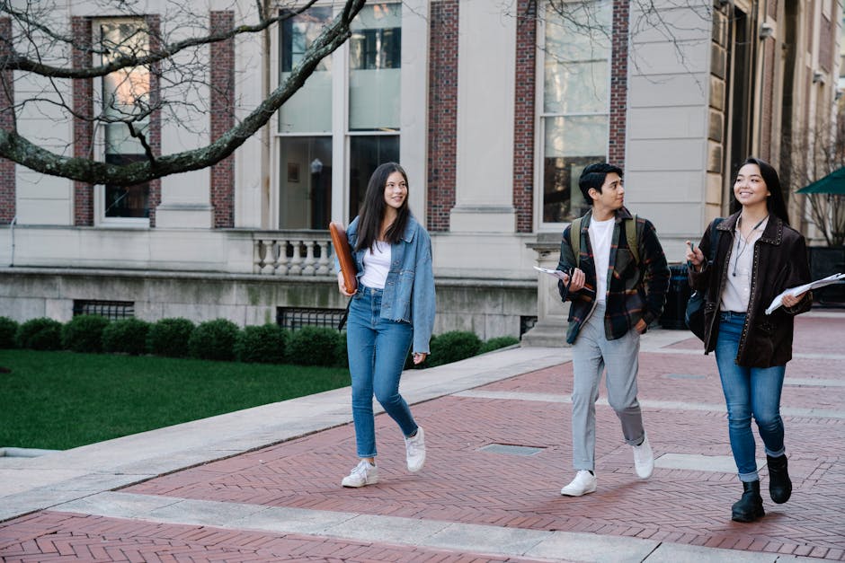 Group of young students walking on campus sidewalk on a bright day, showcasing c